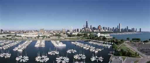 This is an aerial view of the Shedd Aquarium, Chicago Harbor and the skyline on Lake Michigan during summer. Boats are moored in the harbor in the foreground.